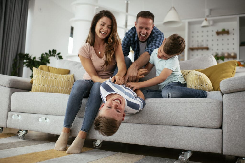 A family playing on a couch in a living room.