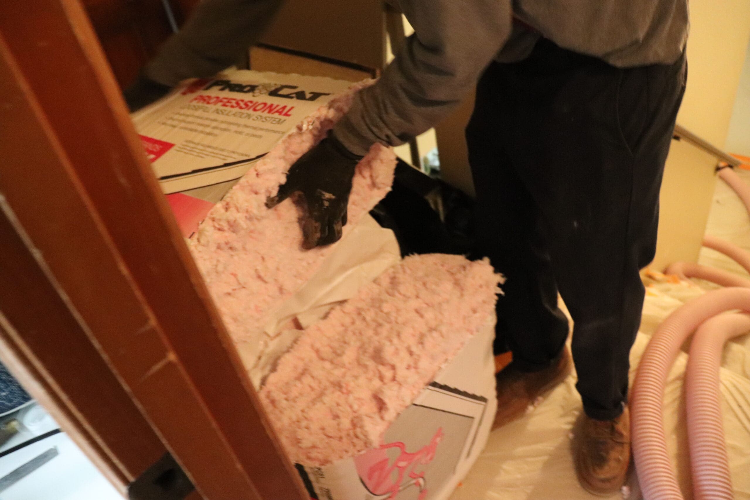 A man is putting pink insulation in a room.