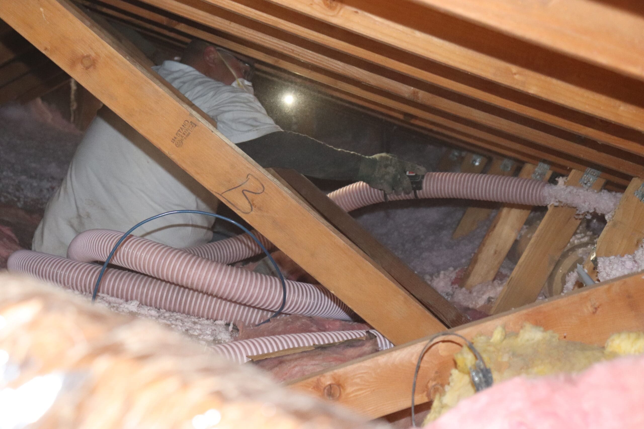 A man is working in an attic with insulation.